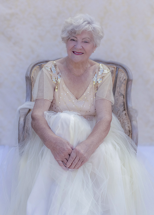 Senior woman in vintage gown sitting in an antique chair
