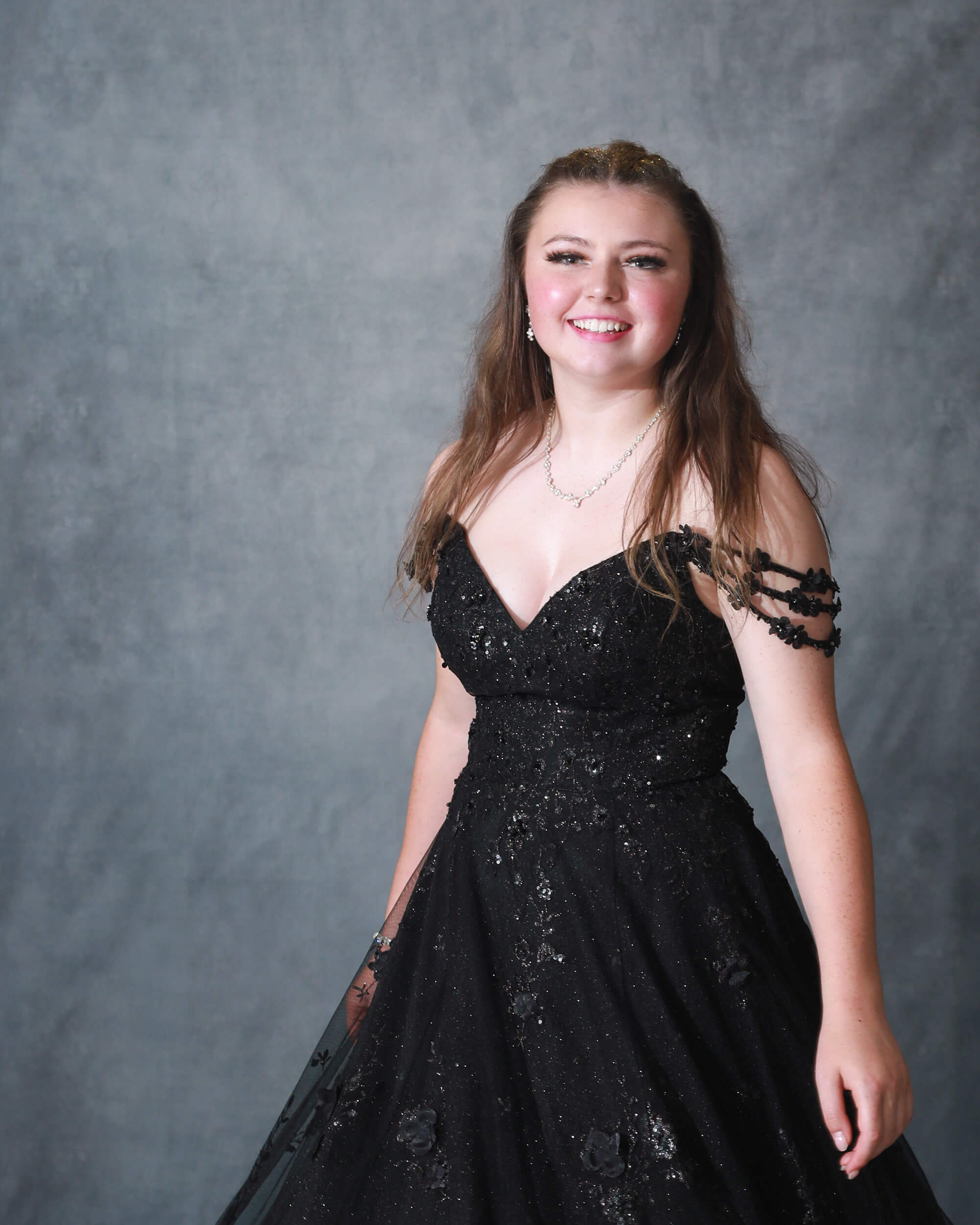 Grad girl is twirling in black lace gown in studio